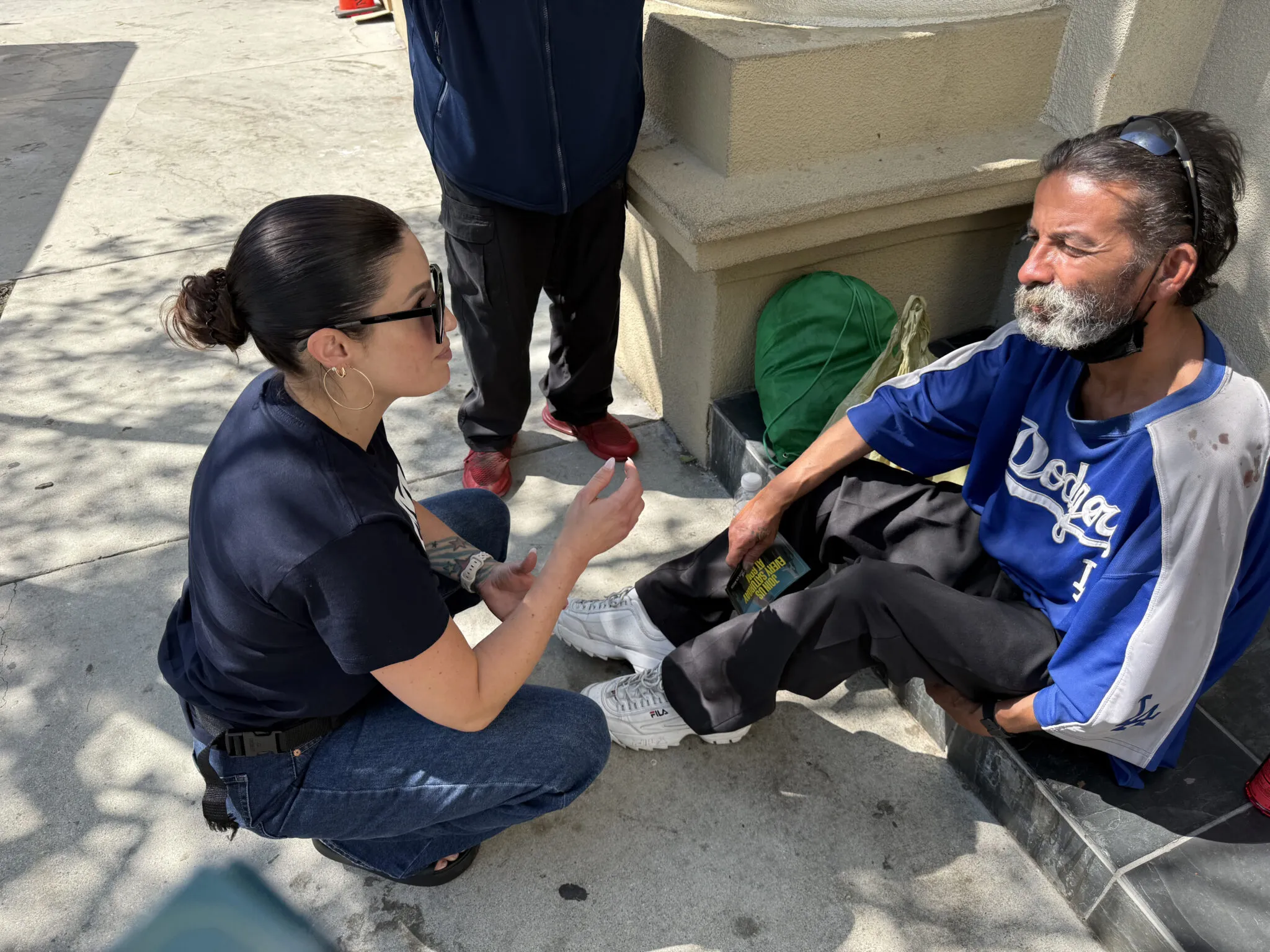 Bridgette kneeling to talk with a man on the street